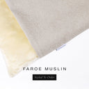 A close up detail of the corner of a Charley Chau Burrow Bag Dog Bed with pale beige outer cover in woven wool texture upholstery fabric Faroe and plush cream faux-fur lining with a woven brand label showing the Charley Chau logo on a white backdrop.