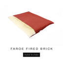 A luxurious Dog Burrow Bag, a sleeping bag style dog bed or snuggle sack style dog bed, with an outer cover in rust red woven wool texture upholstery fabric Faroe with a plush, cream faux-fur lining, and a badge with the colour name Fired Brick on a white background.