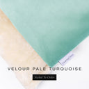 A close up detail of the corner of a Charley Chau Burrow Bag Dog Bed with pale turquoise blue outer cover in upholstery-quality Velour and plush cream faux-fur lining with a woven brand label showing the Charley Chau logo on a white backdrop.