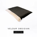 A luxurious Dog Burrow Bag, a sleeping bag style dog bed or snuggle sack style dog bed, with an outer cover in black upholstery-quality Velour with a plush, cream faux-fur lining, and a badge with the colour name Obsidian on a white background.