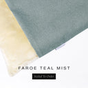 A close up detail of the corner of a Charley Chau Burrow Bag Dog Bed with soft teal grey outer cover in woven wool texture upholstery fabric Faroe and plush cream faux-fur lining with a woven brand label showing the Charley Chau logo on a white backdrop.