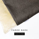 A close up detail of the corner of a Charley Chau Burrow Bag Dog Bed with dark brown outer cover in woven wool texture upholstery fabric Faroe and plush cream faux-fur lining with a woven brand label showing the Charley Chau logo on a white backdrop.