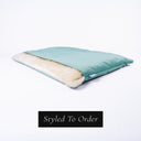 A luxury Dog Burrow Bag - a sleeping bag style dog bed or snuggle sack dog bed - with pale turquoise outer cover in upholstery velour and a plus cream faux-fur lining on a white backdrop with a black badge indicating that the dog bed is a bespoke dog bed and 'Styled To Order'.