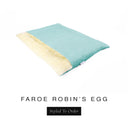 A luxurious Dog Burrow Bag, a sleeping bag style dog bed or snuggle sack style dog bed, with an outer cover in pale aqua woven wool texture upholstery fabric Faroe with a plush, cream faux-fur lining, and a badge with the colour name Robin's Egg on a white background.
