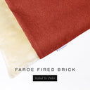 A close up detail of the corner of a Charley Chau Burrow Bag Dog Bed with rust red outer cover in woven wool texture upholstery fabric Faroe and plush cream faux-fur lining with a woven brand label showing the Charley Chau logo on a white backdrop.