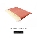 A luxurious Dog Burrow Bag, a sleeping bag style dog bed or snuggle sack style dog bed, with an outer cover in coral orange woven wool texture upholstery fabric Faroe with a plush, cream faux-fur lining, and a badge with the colour name Sienna on a white background.