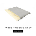 A luxurious Dog Burrow Bag, a sleeping bag style dog bed or snuggle sack style dog bed, with an outer cover in light grey woven wool texture upholstery fabric Faroe with a plush, cream faux-fur lining, and a badge with the colour name Tailor's Grey on a white background.
