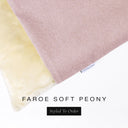 A close up detail of the corner of a Charley Chau Burrow Bag Dog Bed with pale dusty pink outer cover in woven wool texture upholstery fabric Faroe and plush cream faux-fur lining with a woven brand label showing the Charley Chau logo on a white backdrop.