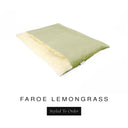 A luxurious Dog Burrow Bag, a sleeping bag style dog bed or snuggle sack style dog bed, with an outer cover in soft olive green woven wool texture upholstery fabric Faroe with a plush, cream faux-fur lining, and a badge with the colour name Lemongrass on a white background.