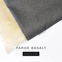A close up detail of the corner of a Charley Chau Burrow Bag Dog Bed with dark grey outer cover in woven wool texture upholstery fabric Faroe and plush cream faux-fur lining with a woven brand label showing the Charley Chau logo on a white backdrop.