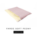 A luxurious Dog Burrow Bag, a sleeping bag style dog bed or snuggle sack style dog bed, with an outer cover in pale dusty pink woven wool texture upholstery fabric Faroe with a plush, cream faux-fur lining, and a badge with the colour name Soft Peony on a white background.