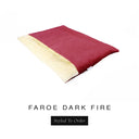 A luxurious Dog Burrow Bag, a sleeping bag style dog bed or snuggle sack style dog bed, with an outer cover in deep red woven wool texture upholstery fabric Faroe with a plush, cream faux-fur lining, and a badge with the colour name Dark Fire on a white background.
