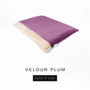 A luxurious Dog Burrow Bag, a sleeping bag style dog bed or snuggle sack style dog bed, with an outer cover in deep plum purple upholstery-quality Velour with a plush, cream faux-fur lining, and a badge with the colour name Plum on a white background.