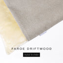 A close up detail of the corner of a Charley Chau Burrow Bag Dog Bed with pale taupe grey outer cover in woven wool texture upholstery fabric Faroe and plush cream faux-fur lining with a woven brand label showing the Charley Chau logo on a white backdrop.