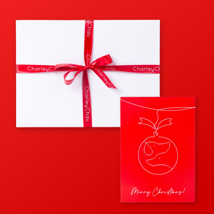 Gift box with a red ribbon and a Christmas card on a red background