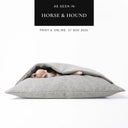Dog sleeping in a luxury Dog Snuggle Bed made to last, a cave bed style dog bed with a soft supoprtive mattress and a built-in blanket cover, in a scrabble resistant upholstery fabric, on a white background with "As seen in Horse & Hound" press feature badge above.