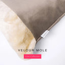 A close up detail of the corner of a Charley Chau Dog Snuggle Bed with taupe brown outer cover in upholstery-quality Velour and plush cream faux-fur lining with a woven brand label showing the Charley Chau logo on a white backdrop.