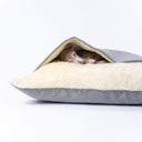 Close up of grey weave dog snuggle bed with cream fleece pocket opening and Italian Greyhound cosy inside.