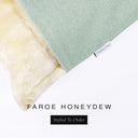 Corner detail of luxury Dog Sngugle Bed in a pale green woven upholstery fabric with a cream faux-fur lining and Charley Chau desigenr brand label.