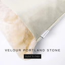 Close up of the corner of a luxury Dog Snuggle Bed, a cave bed style dog bed or sleeping bag style dog bed, with a pale stone grey upholstery-quality velour / velvet outer cover and plush cream faux-fur lining, showing a Charley Chau designer brand label on the dog bed, on a white background.