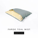 A Charley Chau Snuggle Bed, a cave bed or sleeping bag style dog bed made with a muted teal woven upholstery-quality fabric with cream, plush, faux-fur lining on a white backdrop.