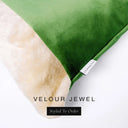 Close up of the corner of a luxury Dog Snuggle Bed, a cave bed style dog bed or sleeping bag style dog bed, with an emerald green upholstery-quality velour / velvet outer cover and plush cream faux-fur lining, showing a Charley Chau designer brand label on the dog bed, on a white background.