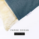 Corner detail of a luxury Dog Snuggle Bed, a sleeping bag style dog bed or cave bed style dog bed, with muted teal blue olored upholstery quality outer cover and plush cream faux-fur lining with Charley Chau's designer brand label.