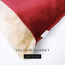 Close up of the corner of a luxury Dog Snuggle Bed, a cave bed style dog bed or sleeping bag style dog bed, with a red upholstery-quality velour / velvet outer cover and plush cream faux-fur lining, showing a Charley Chau designer brand label on the dog bed, on a white background.