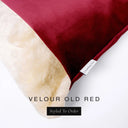 Close up of the corner of a luxury Dog Snuggle Bed, a cave bed style dog bed or sleeping bag style dog bed, with a brick red upholstery-quality velour / velvet outer cover and plush cream faux-fur lining, showing a Charley Chau designer brand label on the dog bed, on a white background.
