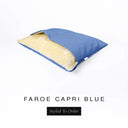 A Charley Chau Snuggle Bed, a cave bed or sleeping bag style dog bed made with a bright blue woven upholstery-quality fabric with cream, plush, faux-fur lining on a white backdrop.