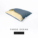 A Charley Chau Snuggle Bed, a cave bed or sleeping bag style dog bed made with a muted teal blue woven upholstery-quality fabric with cream, plush, faux-fur lining on a white backdrop.