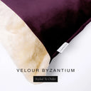 Close up of the corner of a luxury Dog Snuggle Bed, a cave bed style dog bed or sleeping bag style dog bed, with a deep purple upholstery-quality velour / velvet outer cover and plush cream faux-fur lining, showing a Charley Chau designer brand label on the dog bed, on a white background.