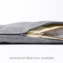 Close up shot of a grey luxury dog travel bed mattress with the zip unzipped revealing a cream waterproof bed liner and white internal mattress insert on a white backdrop.