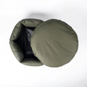 An overhead view of a Charley Chau designer donut dog bed in an olive green, water-resistant cotton canvas, with the round mattress lifted out of the circular donut nest, on a white background.