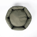 A top-down view of a round / hexagonal donut style dog bed made with an olive green, water-resistant dog bed fabric, on a white background.