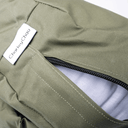 Close-up of an olive green, water-resistant dog bed mattress with a white sewn-in label reading 'Charley Chau' and a black zipper partially open to reveal a white mattress inside.