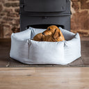 A dachshund dog lying in a pale blue calming donut dog bed.