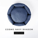 A top-down view of a dark navy blue luxury donut dog bed with high-wall padded sides and a round mattress inside, on a white background with the text 'COSMO NAVY SHADOW' and a black 'Styled To Order' label below.