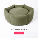 A khaki / olive green luxury donut dog bed, suitable for all breeds of dogs, with cosy, high-wall dog bed sides and a deepfilled luxury mattress inside, on a white background with the text 'COSMO FERN' and 'Core Collection' below.