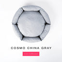 A top-down view of a light blue-gray circular donut style dog bed with high-wall padded sides and a round mattress inside, shown on a white background with the text 'COSMO CHINA GRAY' and a pink 'Core Collection' label below.