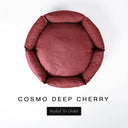 A top-down view of a deep cherry red luxury donut dog bed with high-wall padded sides and a round mattress inside, on a white background with the text 'COSMO DEEP CHERRY' and a black 'Styled To Order' label below.
