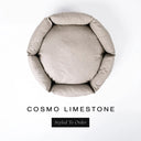 A top-down view of a pale limestone grey luxury donut dog bed with high-wall padded sides and a round mattress inside, on a white background with the text 'COSMO LIMESTONE' and a black 'Styled To Order' label below.