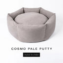 A luxury donut dog bed in warm putty grey Cosmo fabric, suitable for all breeds of dogs, with cosy high-wall sides and a deep-filled luxury mattress inside, on a white background with the text 'COSMO PALE PUTTY' and 'Styled To Order' below.