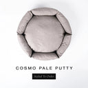 A top-down view of a warm putty grey luxury donut dog bed with high-wall padded sides and a round mattress inside, on a white background with the text 'COSMO PALE PUTTY' and a black 'Styled To Order' label below.