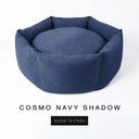 A luxury donut dog bed in dark navy blue Cosmo fabric, suitable for all breeds of dogs, with cosy high-wall sides and a deep-filled luxury mattress inside, on a white background with the text 'COSMO NAVY SHADOW' and 'Styled To Order' below.