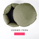 A luxury donut dog bed in muted khaki-green Cosmo fabric seen from above with the round mattress lifted out of the high-wall donut bed sides, on a white background with the text 'COSMO FERN' and a pink 'Core Collection' label.