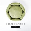 A top-down view of a soft pistachio green luxury donut dog bed with high-wall padded sides and a round mattress inside, on a white background with the text 'COSMO PISTACHIO' and a black 'Styled To Order' label below.