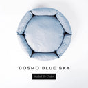 A top-down view of a soft sky blue luxury donut dog bed with high-wall padded sides and a round mattress inside, on a white background with the text 'COSMO BLUE SKY' and a black 'Styled To Order' label below.