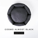 A top-down view of a charcoal black luxury donut dog bed with high-wall padded sides and a round mattress inside, on a white background with the text 'COSMO ALMOST BLACK' and a black 'Styled To Order' label below.