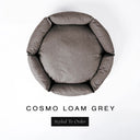 A top-down view of a warm taupe grey luxury donut dog bed with high-wall padded sides and a round mattress inside, on a white background with the text 'COSMO LOAM GREY' and a black 'Styled To Order' label below.
